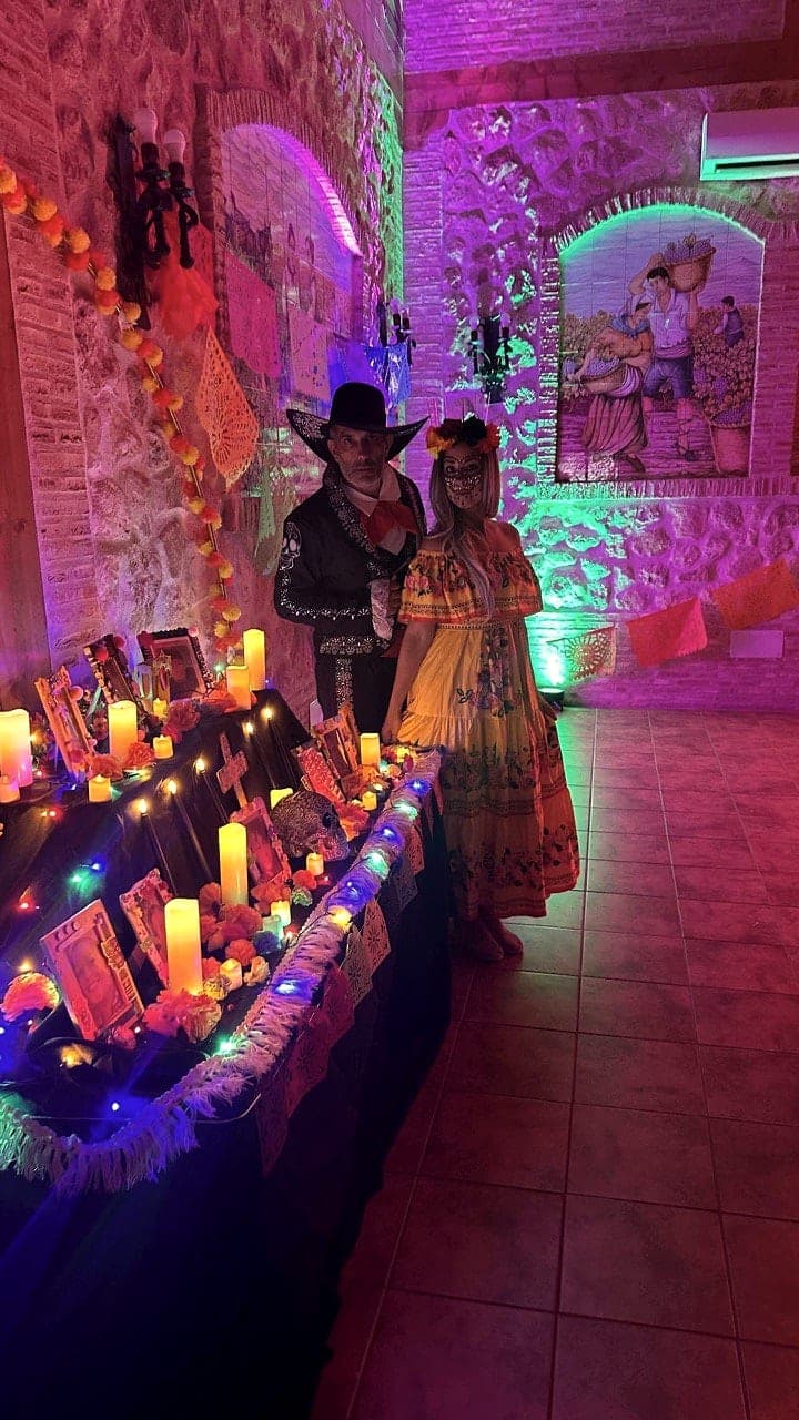 Altar de muertos con velas y una pareja de catrines
