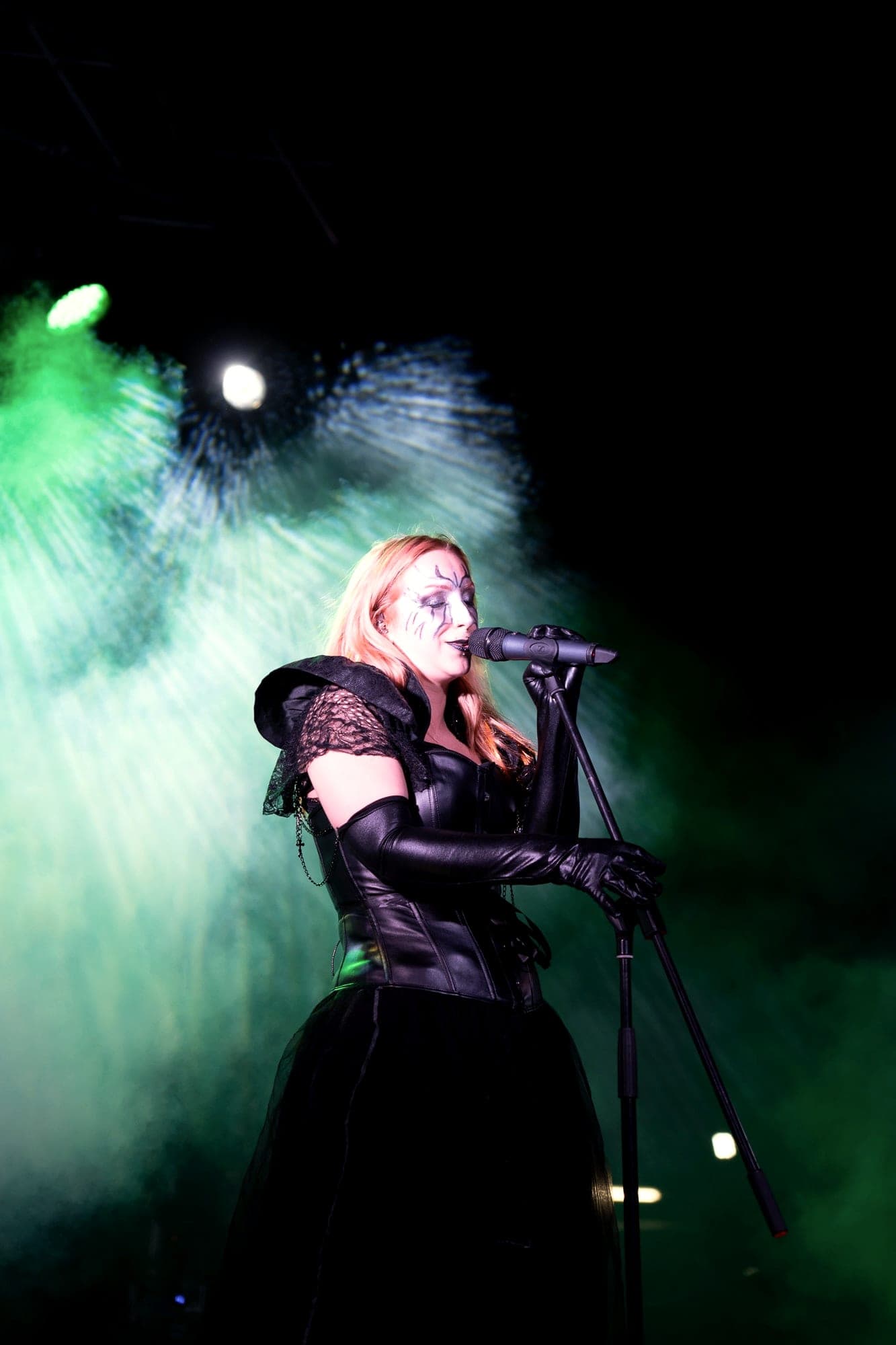 Costumed singer under a spotlight with green light