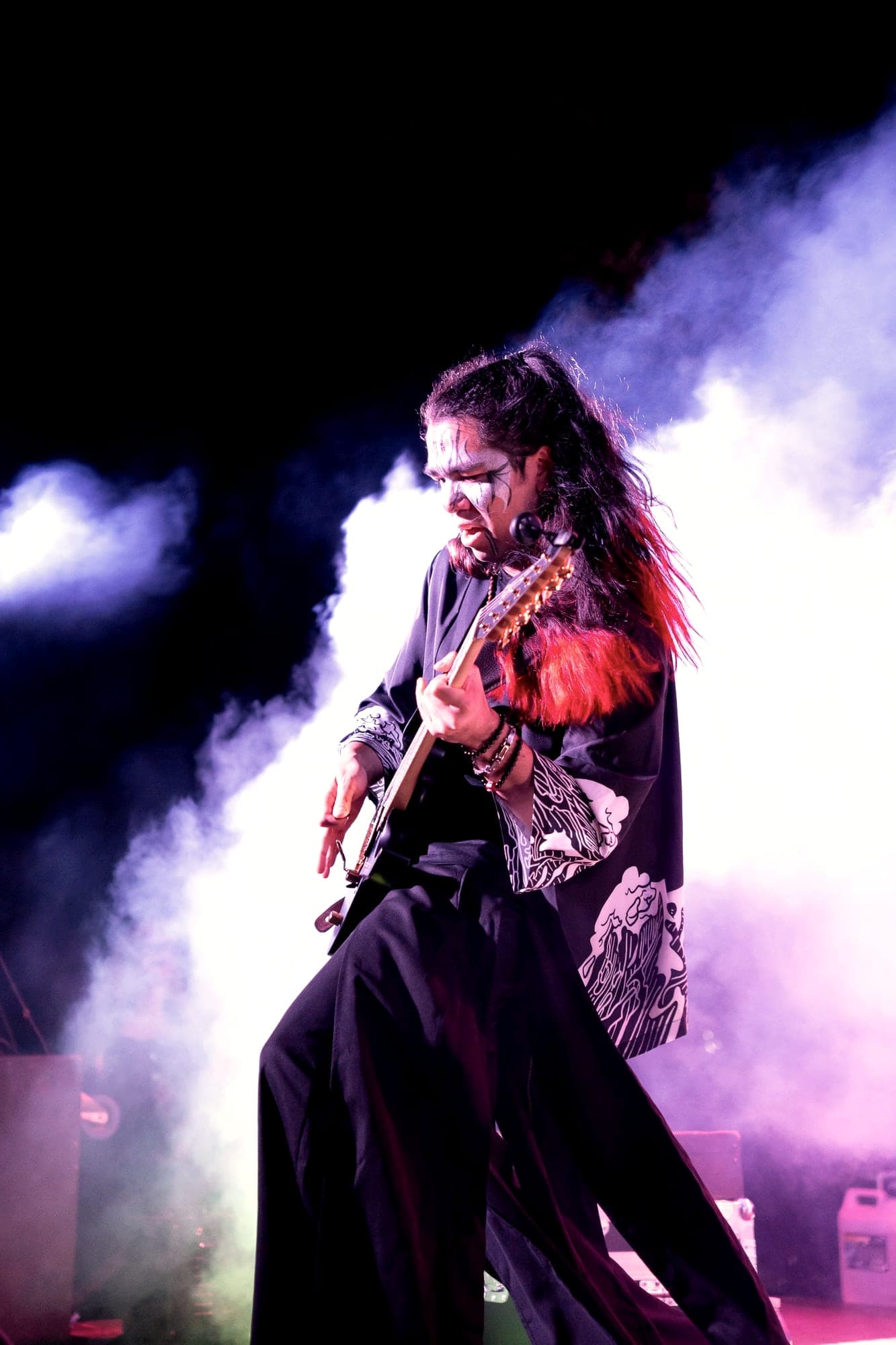 Guitarrista caracterizado entre humo y luz violeta