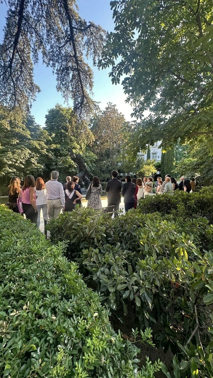 Invitados reunidos en un jardín arbolado al atardecer